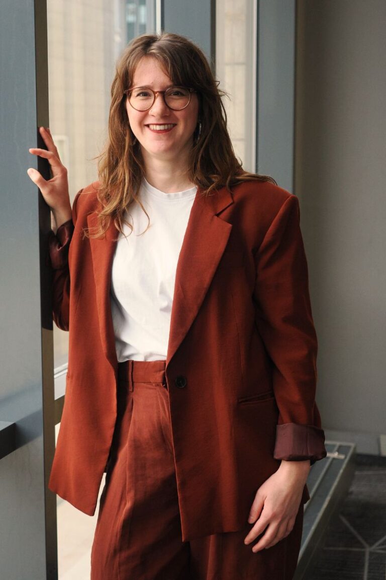 Lea Najork vor einer verglasten Fensterfront in einem roten Anzug.